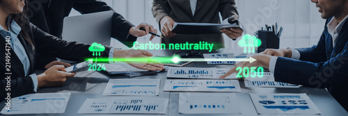 Foto Group of professionals engaged in a business meeting discussing plans for achieving carbon neutrality by 2050, featuring reports, charts, and strategic documents