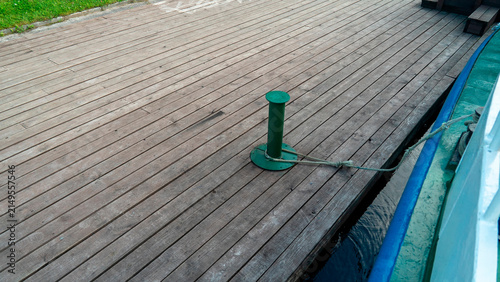 Green mooring post on wooden dock near water in a harbor on a clear day