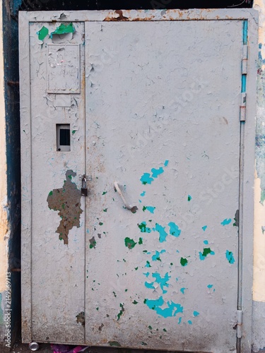 Fotografie Old metal door with peeling paint in urban alley