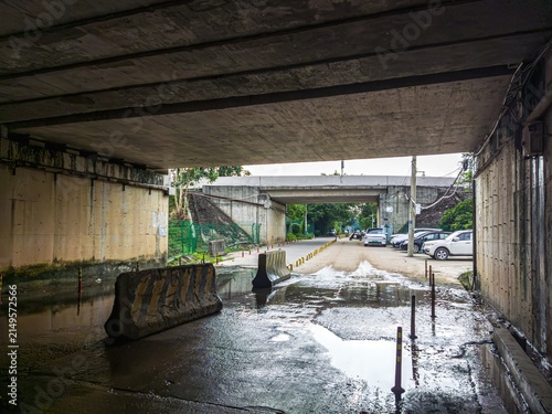 Canvastavla Concrete underpass with wet road and parked cars