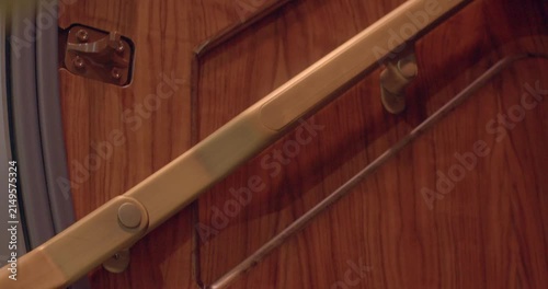 Brass handrail hinge installed on wood with visible tension and screws. Closeup image showcasing brass hinge attached to wooden surface with tension and screw details visible