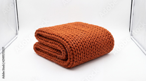 Folded Knit Blanket in Warm Amber: A neatly folded knit blanket in a rich, warm amber hue, showcasing its textured weave and cozy appeal. A perfect accent for home comfort.