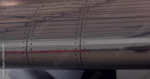 Jet wing wear inspection ongoing. Closeup of wing surface scratches observed. Assessment of jet wing scratches and protective coating condition by inspection team