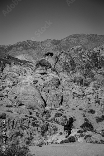 Hiking to Heart Rock. Three people hike through the Alabama Hills toward the Heart Rock. The rock has a hole shaped like a heart.
