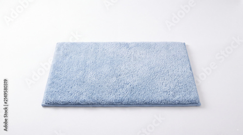 Soft Blue Bath Mat: A fluffy, light blue bath mat lies on a clean white surface, offering a touch of comfort and style to any bathroom setting.