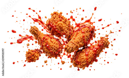 Fototapeta kuchenna Crispy fried chicken drumsticks with spicy red sauce splashing isolated on transparent background