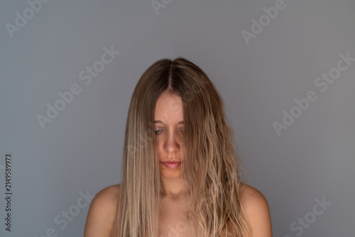 Young blonde woman showing porous wavy and straight hair comparison after keratin straightening, lamination or flat iron styling, nanoplasty, beauty haircare concept on gray background