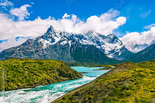 Obraz na plátně Churning white rapids of a mountain river flowing into a bright turquoise lake beneath dramatic snow-dusted peaks in Torres del Paine