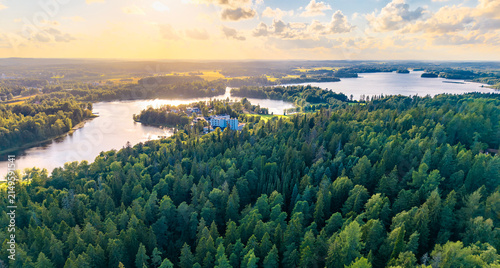 Scenic aerial landscape from Finland with dense forest and a water in sunset with distant buildings. 
