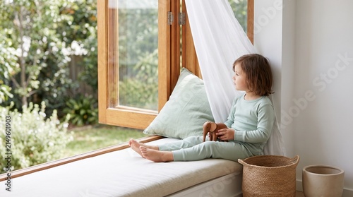 Child rests by an open window in a fresh healthy home