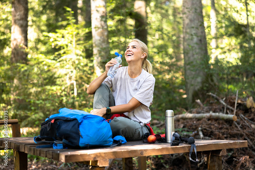 фотографія Happy woman taking a break on a forest hike, hydrating and laughing while sittin