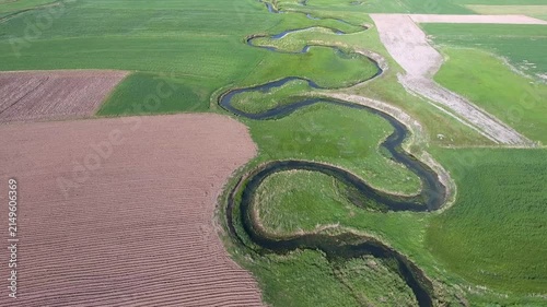 Aerial view of river meander flowing through agricultural fields on a flat plain in France.