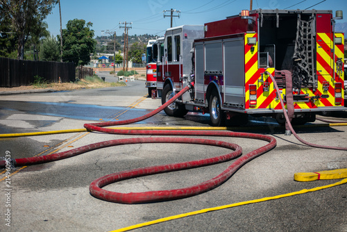Firemen and women practicing to put out fires on an abandoned house looking at a fire hose on the ground