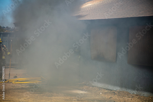 Firemen and women practicing to put out fires on an abandoned house looking at