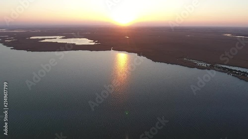 Aerial sunrise over still lake surrounded by reeds in vast northern wetland landscape.