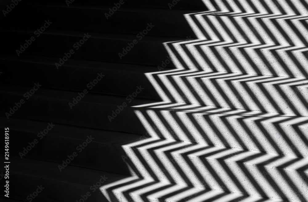 Naklejka premium Stark zigzag shadow pattern on dark, modern stairs