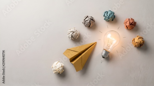 Startup success and inspiration concept showing a paper plane taking off next to a glowing lightbulb