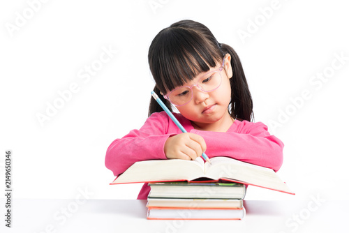 Фотография Diligent girl with glasses writing on big book pile of books