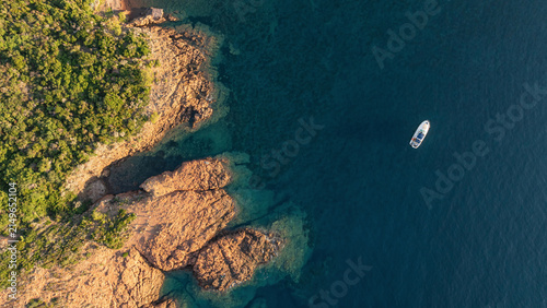 Fotografía Top down aerial view of a boat anchored near the red cliffs of the Esterel coast