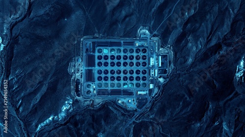 Top down aerial view of four massive nuclear power plant cooling towers with dark circular openings surrounded by dense forest in a green night vision map style