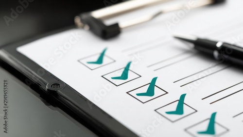 A paper checklist with a pen represents organized evaluation and completed administrative tasks.
