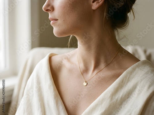 Close-up of woman wearing delicate gold pendant necklace, quiet luxury jewelry