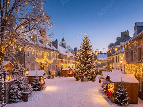 Christmas market in snowy old town square with illuminated tree and festive lights