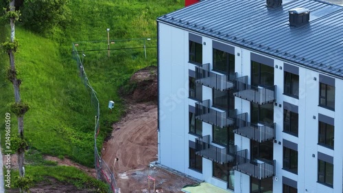 New modern residential building with balconies standing next to an undeveloped construction area