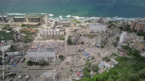 Slow motion drone pan reveals widespread earthquake destruction, collapsed buildings and coastal urban damage in La Guaira, Venezuela.