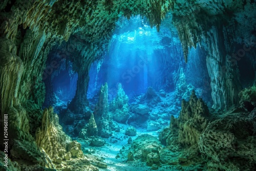 Underwater view inside ocean cave with sunlight beam entering blue water