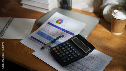 Financial planning workspace with calculator, budget documents, laptop, and coffee on a wooden desk, representing personal finance, accounting, and expense management.