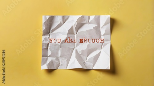 Yellow background with handwritten crumpled note YOU ARE ENOUGH , positive self-talk affirmation to boost self-esteem, build self-worth and develop self-respect