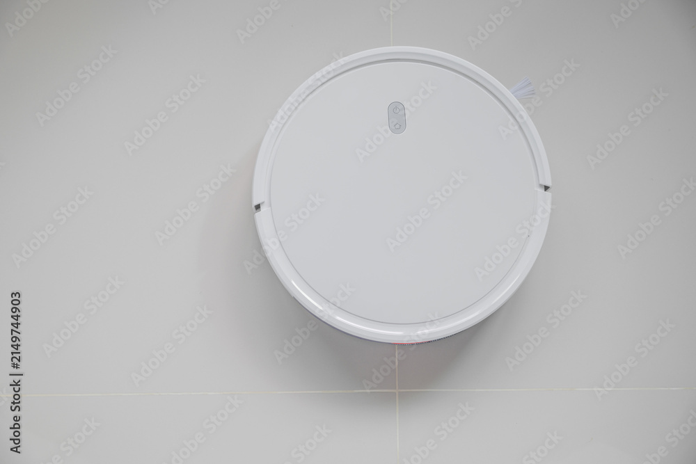 Foto White automatic floor cleaner with side brush on tile flooring