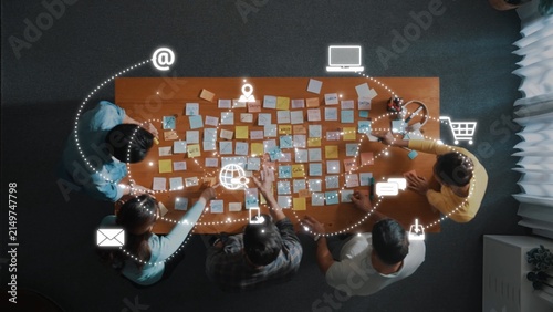 Fotografía A diverse team collaborates over a table filled with sticky notes, integrating technology and communication tools for effective project planning in a modern office