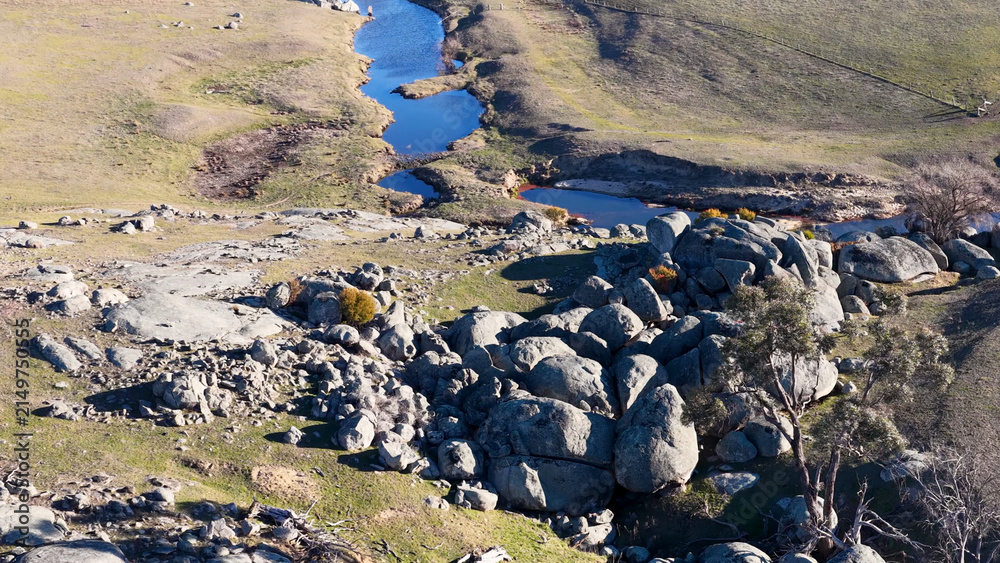 Obraz premium Aerial View of Granite Boulders and Winding River in Uralla Countryside