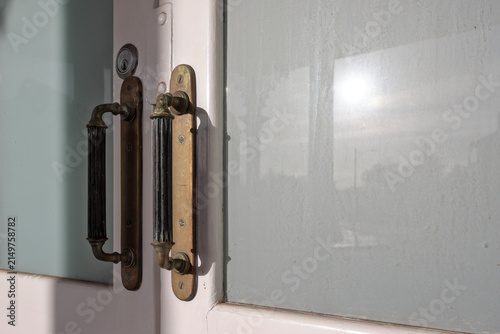 Cuadro en lienzo Close-up of vintage ornate brass handles on double white painted wooden doors wi