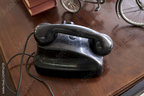 Foto Vintage black bakelite telephone with handset on a polished dark wood desk surface