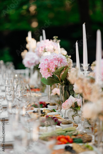 Fotografía Elegant outdoor banquet table with pink hydrangeas, tall candles, and diverse ap