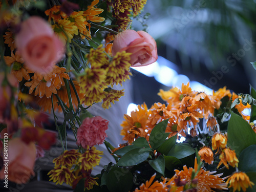 Fotografie Colorful autumn floral arrangement with orange chrysanthemums, red roses and warm seasonal flowers against a lush green background with soft circular bokeh
