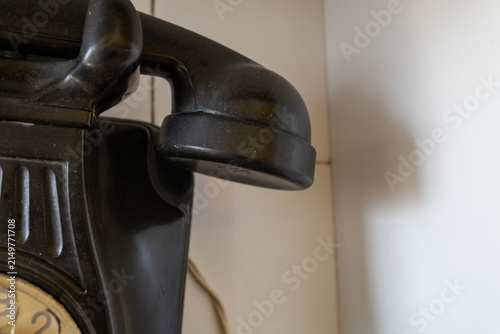 Photography Close-up of an antique black bakelite rotary telephone handset resting on its cr
