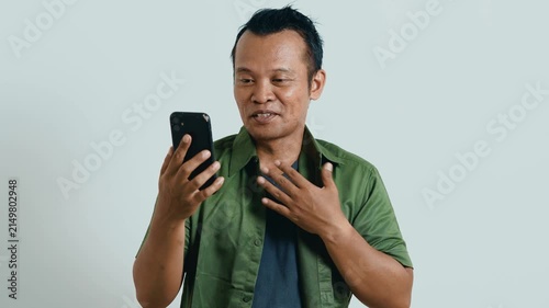 Video call. Portrait of man talking on smartphone or using virtual personal assistant app on his device. Asian man recording video call with mobile phone.