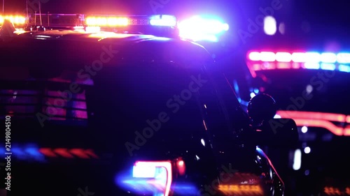 Multiple police vehicles with flashing blue and red emergency lights illuminating a dark night scene with motion.