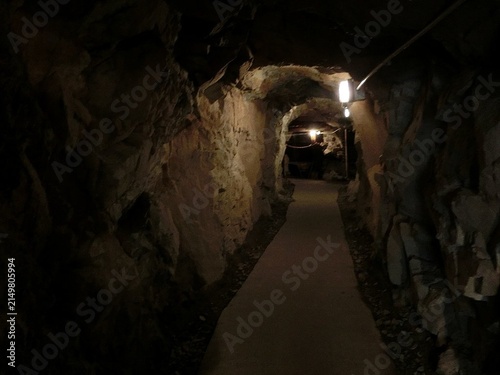 Fotografía Underground Mine Tunnel with Rough Stone Walls and Artificial Lighting