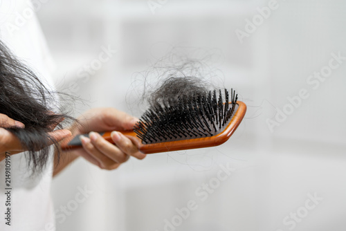 Obraz na plátne Close up of a woman brushing long hair with loose strands caught in a hairbrush