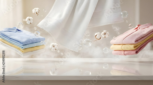 Fresh floating laundry with cotton bolls and bubbles over white surface