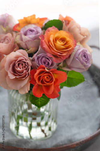 ガラス花瓶に活けられたオレンジやパープルの色鮮やかなバラの花束