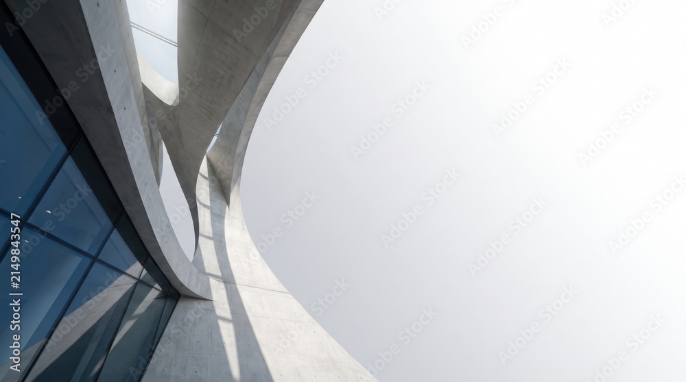 Fototapeta premium Modern architectural detail of a concrete building with curved structural elements and glass facade against a bright sky