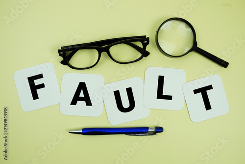 FAULT alphabet letters with magnifying glass, eye glasses and pen on yellow background