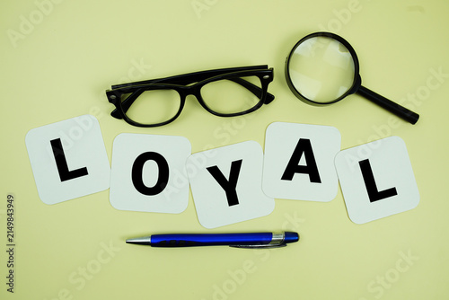LOYAL alphabet letters with magnifying glass, eye glasses and pen on yellow background