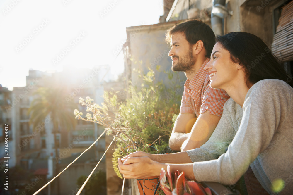 Obraz premium Thinking, couple and smile at house on balcony, love and bonding together on calm morning. Happy, people and daydreaming on terrace for stress relief, affection and sightseeing view for weekend break